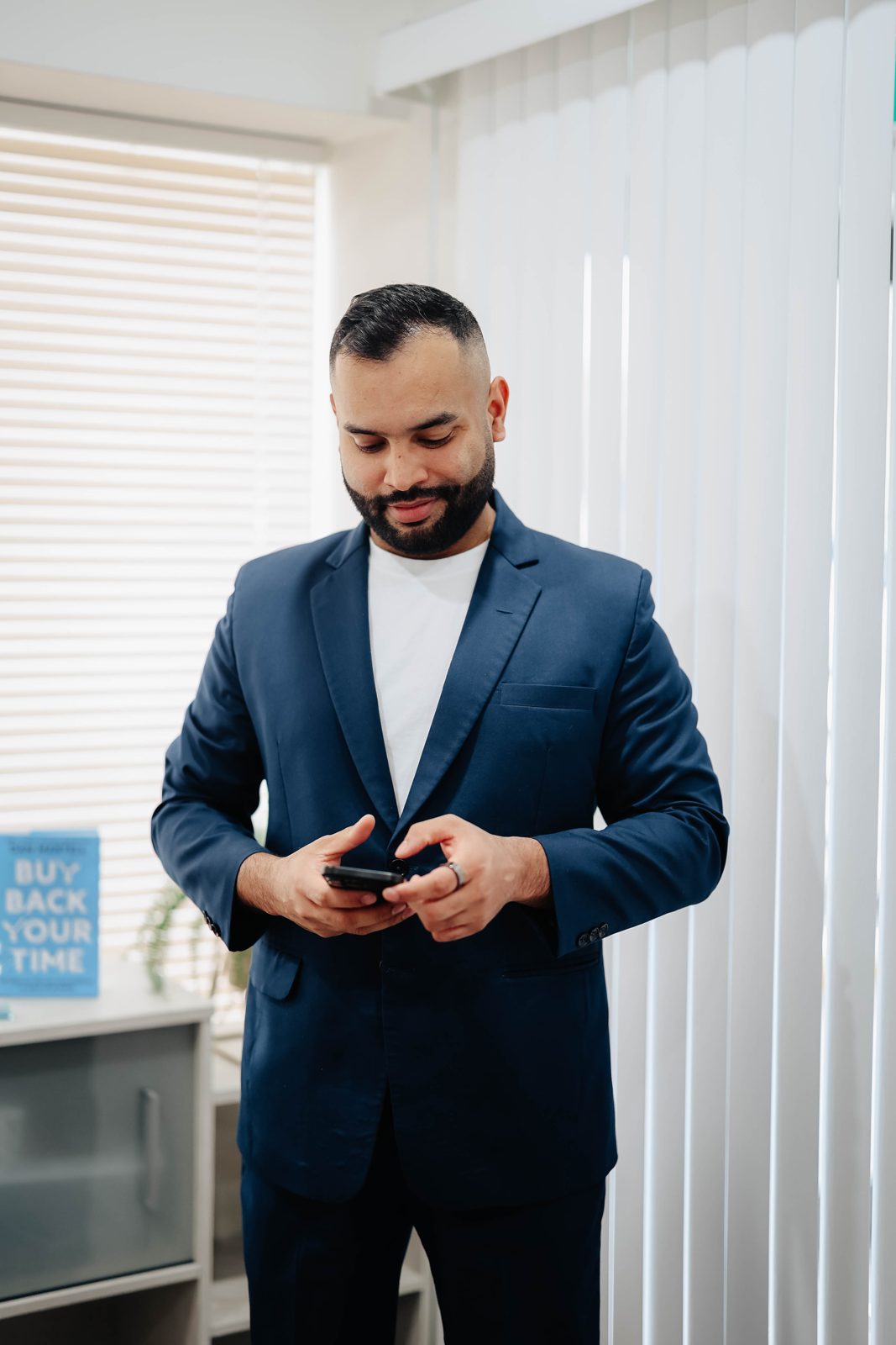 Rahul Bedi standing in the Team Active Mortgage office checking his phone
